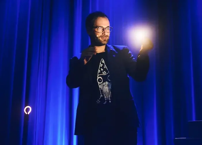 Zauberer Phil Schmitz zeigt ein Lichttrick vor einem blauen Vorhang